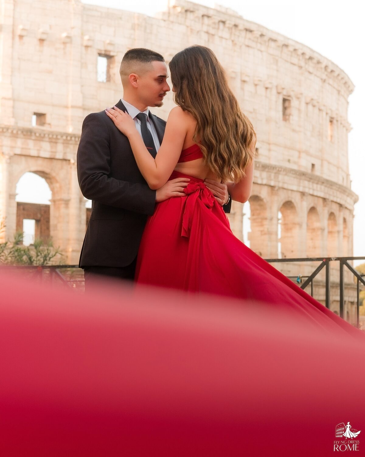 Servizio flying dress al Colosseo all'alba, Roma — coppia abbracciata con abito rosso